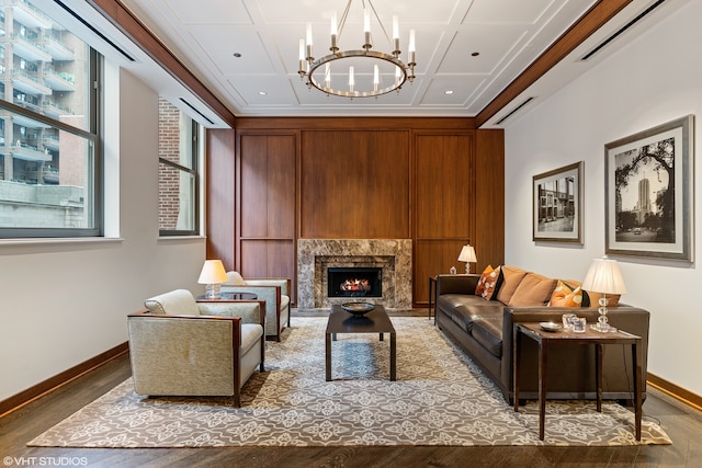 sitting room with coffered ceiling, an inviting chandelier, a high end fireplace, crown molding, and hardwood / wood-style floors