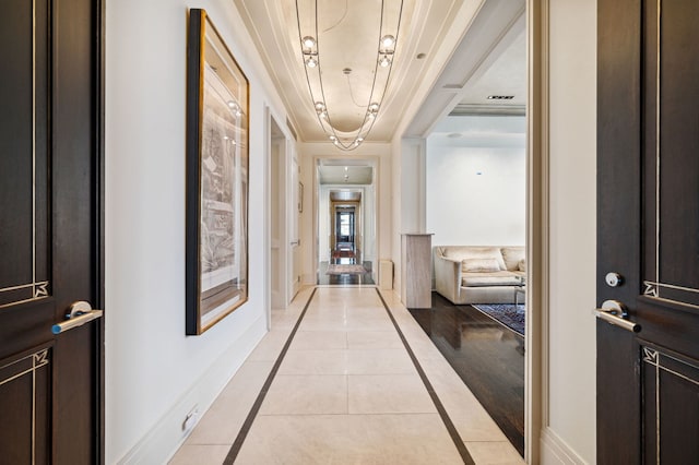 corridor with crown molding and light tile patterned flooring