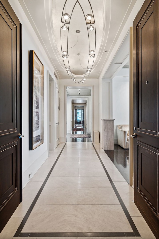 corridor with a raised ceiling and light tile patterned floors