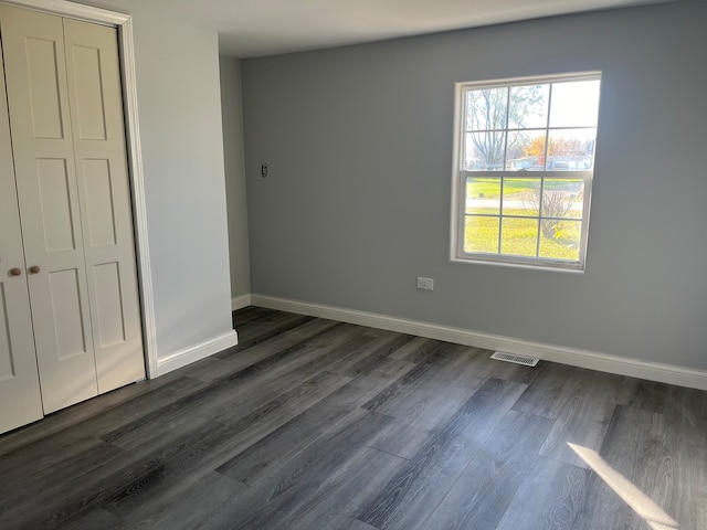 unfurnished bedroom featuring a closet and dark wood-type flooring