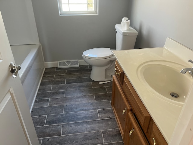 bathroom with a tub to relax in, vanity, and toilet