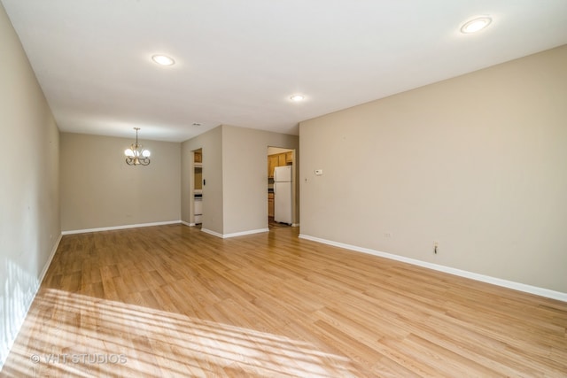 spare room featuring light hardwood / wood-style flooring and a notable chandelier