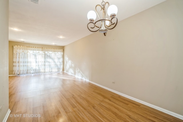 unfurnished room featuring a notable chandelier and light hardwood / wood-style floors