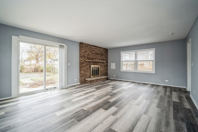 unfurnished living room featuring light hardwood / wood-style floors and a brick fireplace