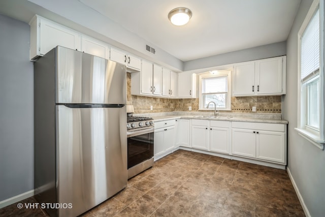 kitchen with white cabinets, appliances with stainless steel finishes, and backsplash