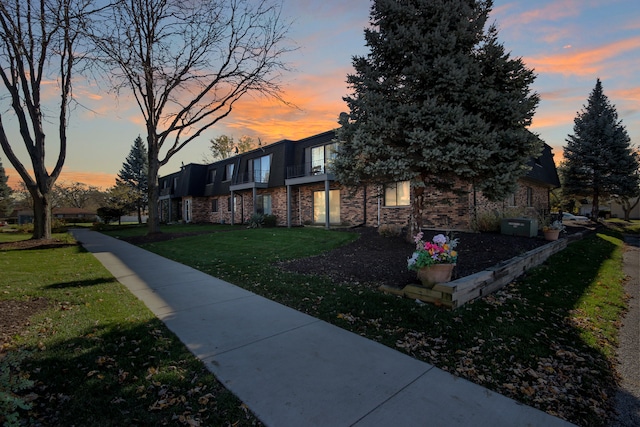 property exterior at dusk featuring a lawn