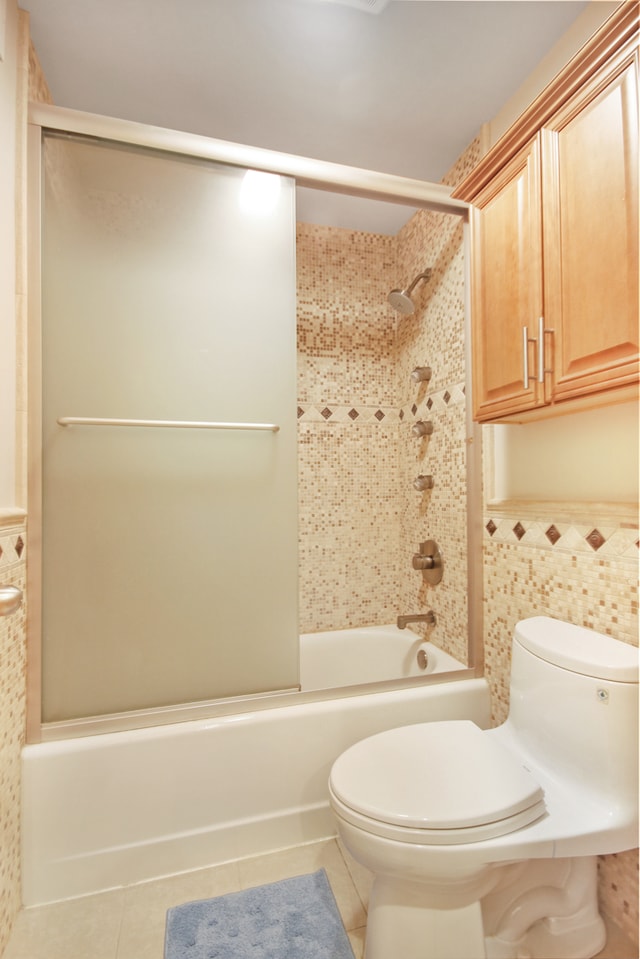 bathroom with tile patterned flooring, toilet, tile walls, and enclosed tub / shower combo