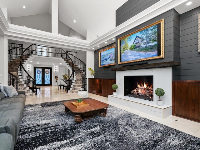 living room with wood walls, a high end fireplace, high vaulted ceiling, and light tile patterned floors