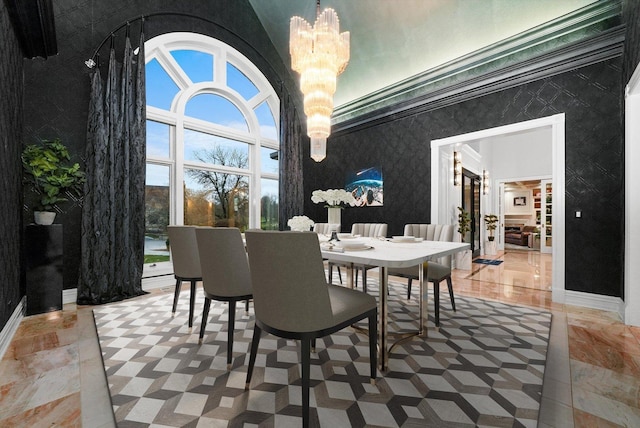 dining space featuring a high ceiling, baseboards, a chandelier, and wallpapered walls