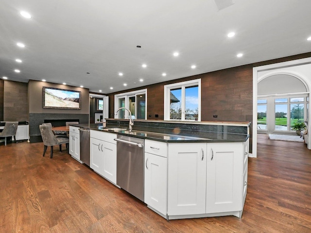 kitchen featuring dark hardwood / wood-style floors, an island with sink, sink, white cabinets, and stainless steel dishwasher