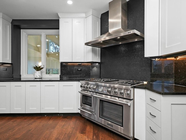 kitchen with range with two ovens, wall chimney range hood, and white cabinets