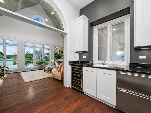 bar with white cabinetry, sink, beverage cooler, and a water view