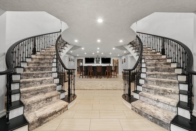 stairs featuring bar and a textured ceiling