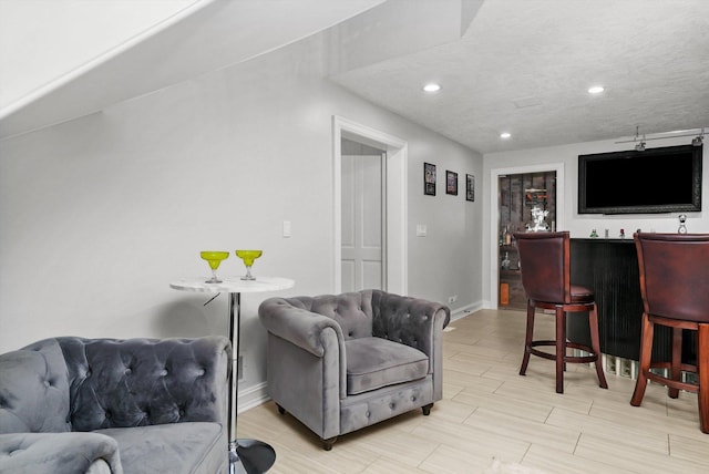 living room with indoor bar, a textured ceiling, and light wood-type flooring