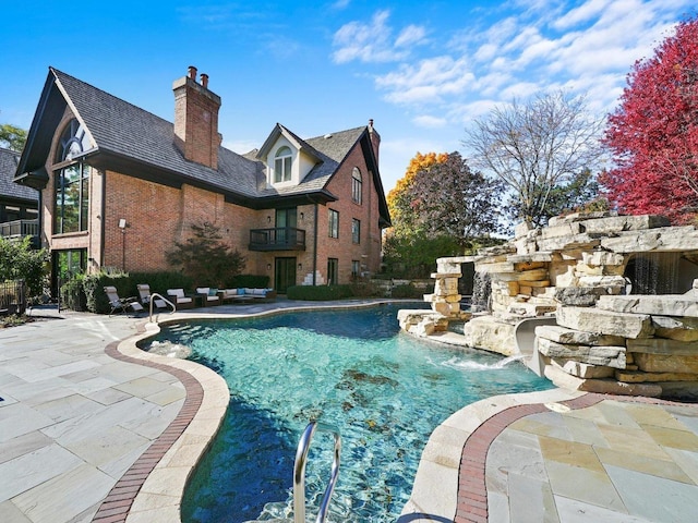 view of swimming pool with pool water feature and a patio