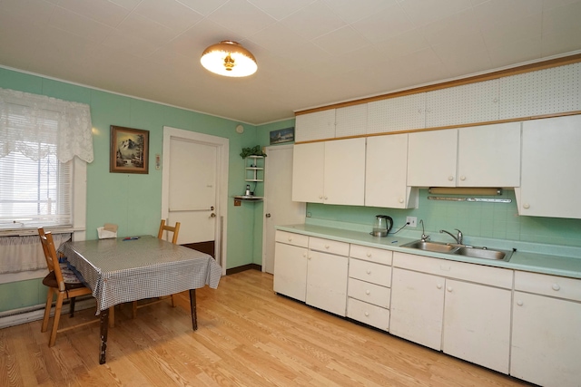 kitchen with backsplash, sink, white cabinets, and light hardwood / wood-style floors