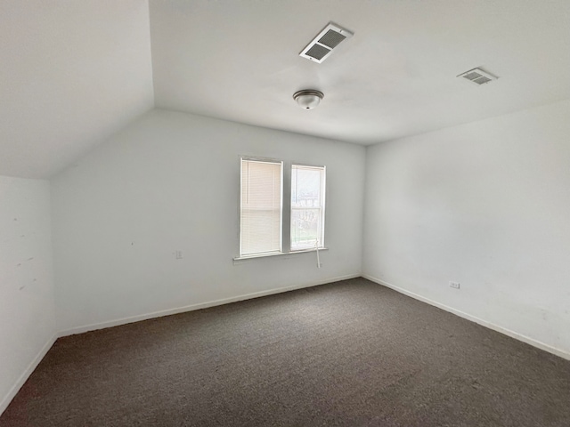 additional living space featuring dark carpet and vaulted ceiling