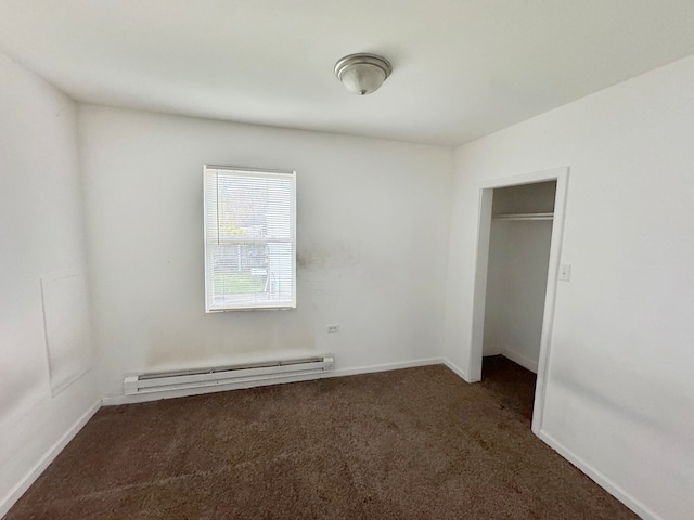 unfurnished bedroom with dark colored carpet, a closet, and baseboard heating