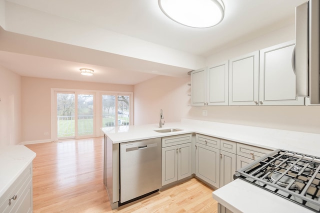 kitchen with kitchen peninsula, light wood-type flooring, stainless steel dishwasher, and sink