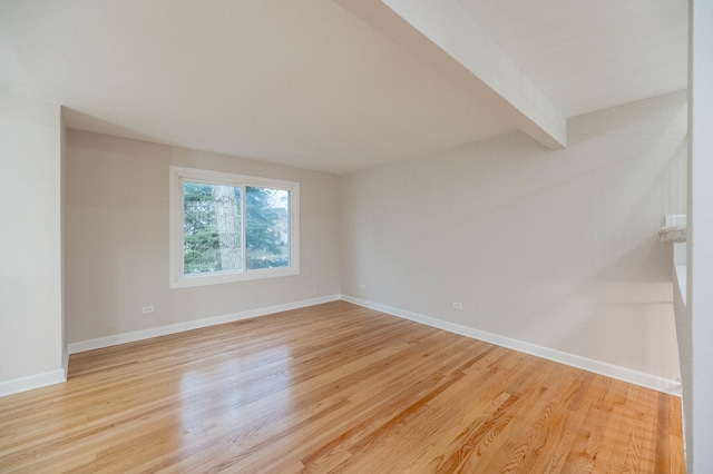 unfurnished room featuring light hardwood / wood-style flooring and beamed ceiling