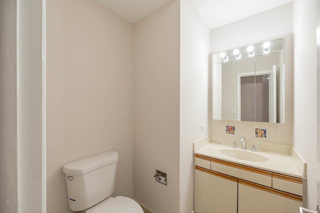 bathroom with backsplash, vanity, and toilet