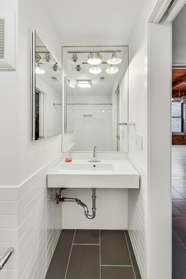 bathroom with tile patterned floors, sink, and tile walls