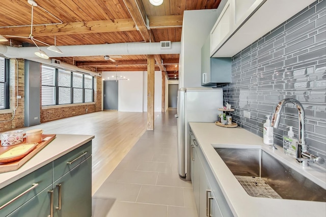 kitchen featuring decorative backsplash, brick wall, sink, pendant lighting, and beamed ceiling