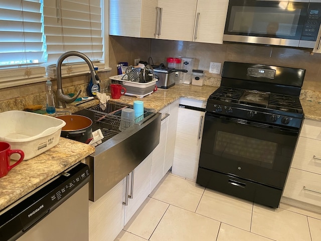 kitchen featuring light stone countertops, appliances with stainless steel finishes, tasteful backsplash, and light tile patterned flooring