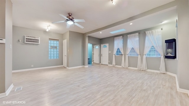 spare room with ceiling fan, light wood-type flooring, and an AC wall unit