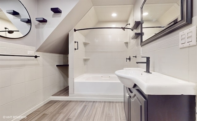 bathroom with tiled shower / bath, vanity, tile walls, and hardwood / wood-style flooring