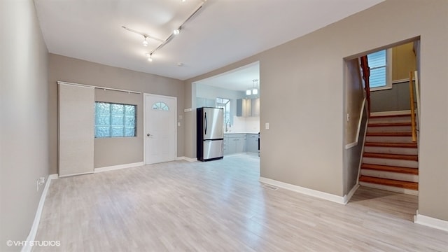 unfurnished room with track lighting and light wood-type flooring