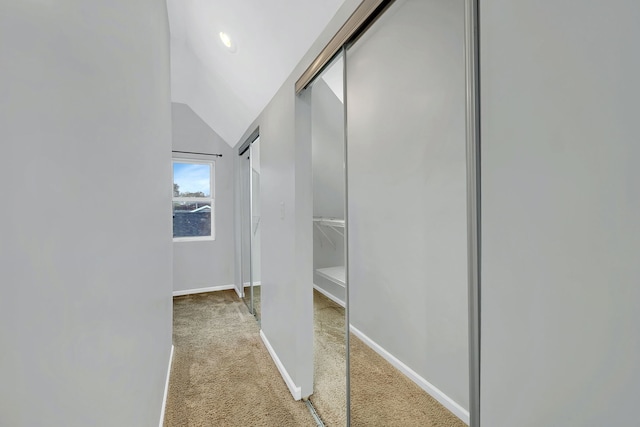 hall featuring light colored carpet and lofted ceiling