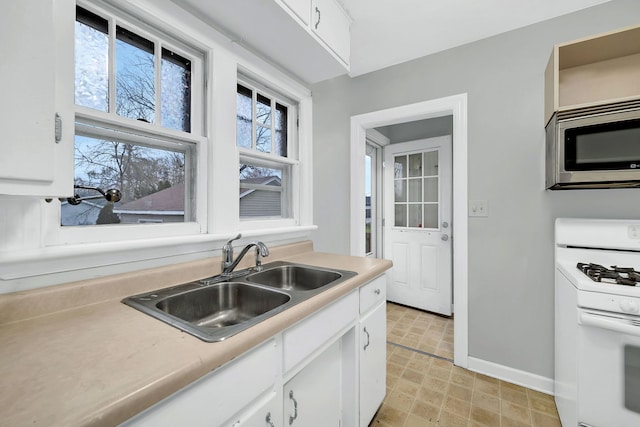 kitchen featuring white cabinets, white range with gas stovetop, and sink