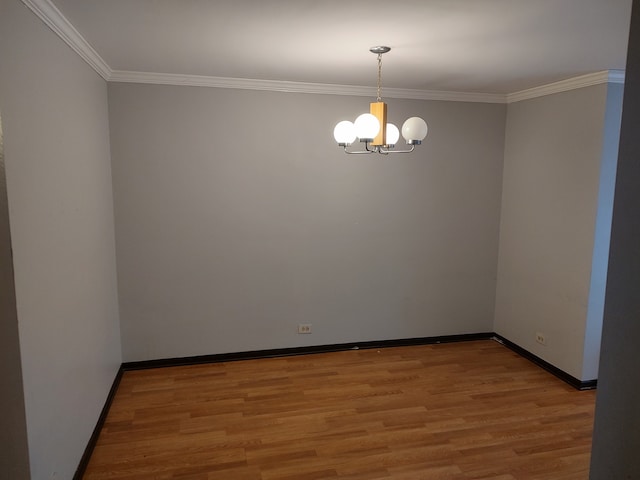 empty room with hardwood / wood-style flooring, ornamental molding, and a chandelier