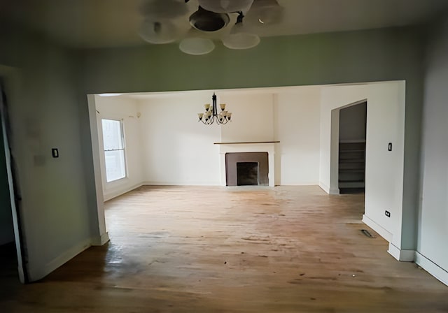 unfurnished living room with a chandelier and hardwood / wood-style flooring