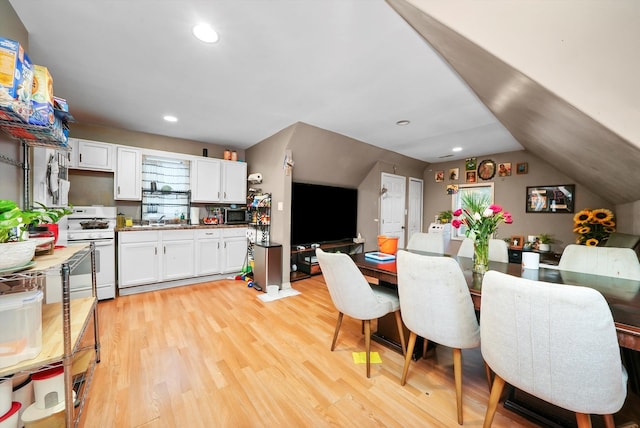 dining area featuring sink, vaulted ceiling, and light wood-type flooring