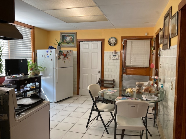 kitchen featuring light tile patterned floors, white fridge, and tile walls