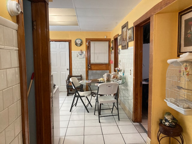 dining space with light tile patterned floors and tile walls