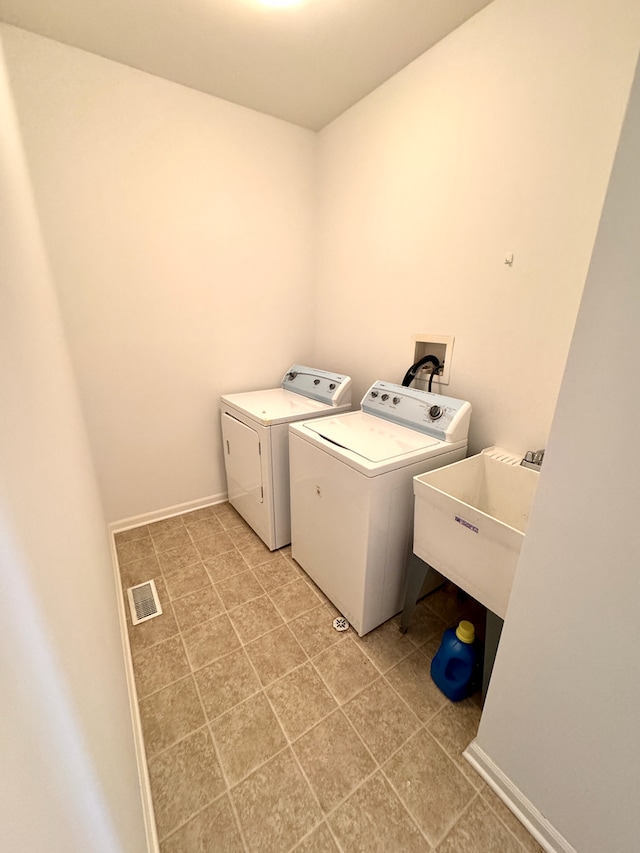 clothes washing area with separate washer and dryer and sink