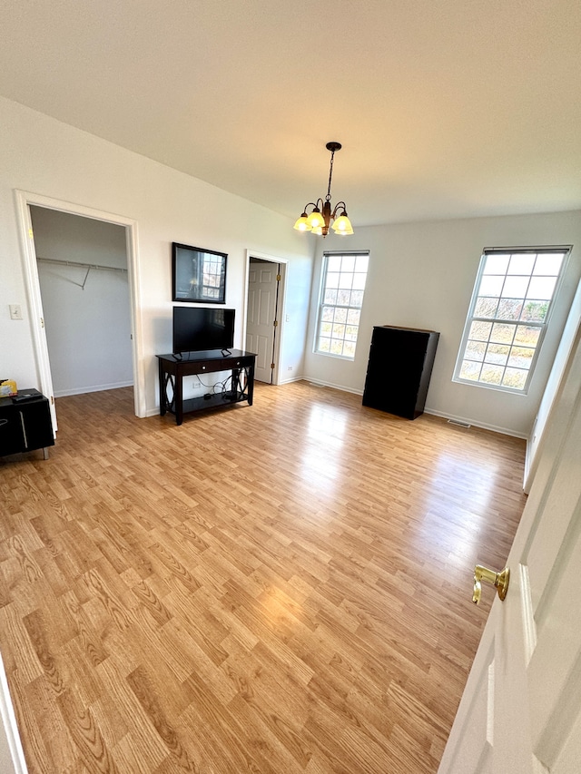 living room with an inviting chandelier, light hardwood / wood-style flooring, and plenty of natural light