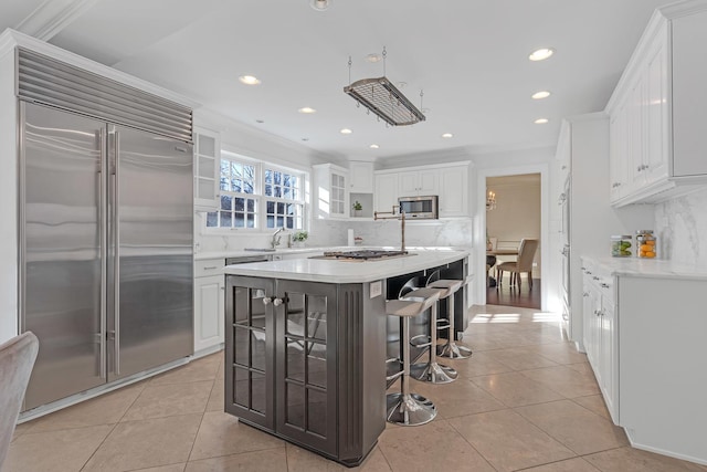 kitchen featuring stainless steel appliances, a kitchen island, white cabinets, and a kitchen bar