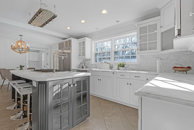 kitchen with white cabinetry, sink, ornamental molding, a center island, and light tile patterned floors