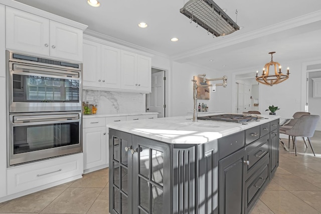 kitchen featuring ornamental molding, stainless steel appliances, an island with sink, and white cabinets