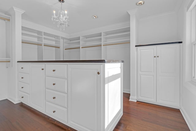 spacious closet with dark wood-type flooring and a chandelier