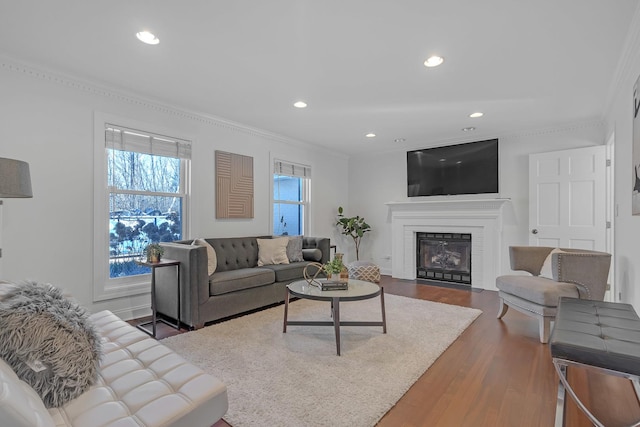 living room with hardwood / wood-style flooring, crown molding, and a brick fireplace