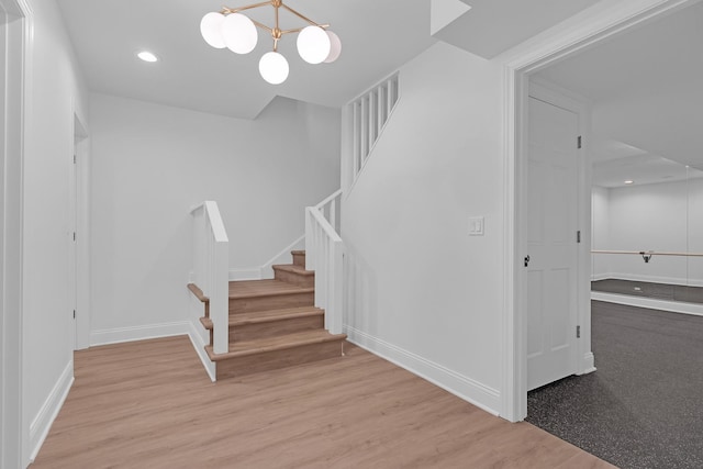 staircase featuring an inviting chandelier and hardwood / wood-style floors