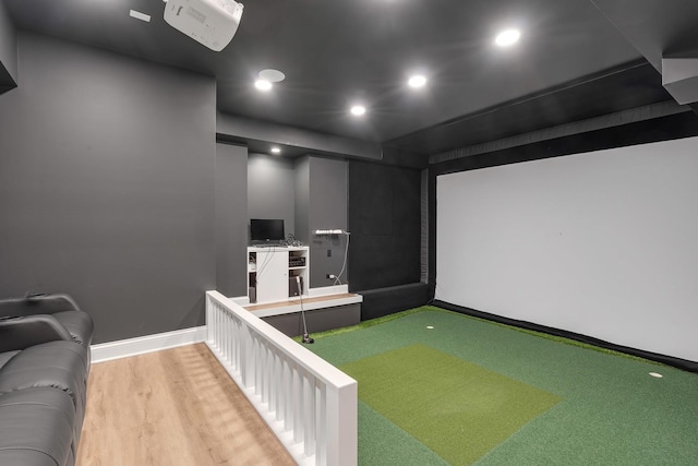 home theater room featuring golf simulator and light hardwood / wood-style floors