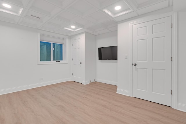 unfurnished room with beamed ceiling, coffered ceiling, and light hardwood / wood-style floors