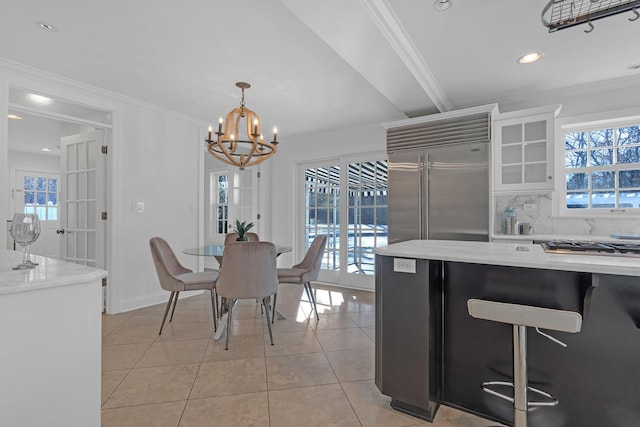 tiled dining space with ornamental molding and a chandelier