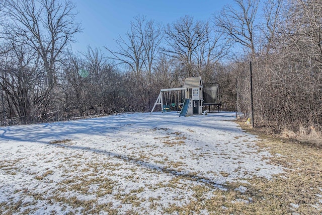 snowy yard featuring a playground